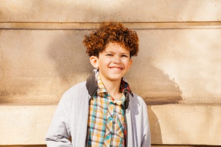 Cuban curly-haired boy standing against the wall