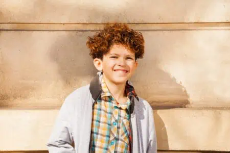 Cuban curly-haired boy standing against the wall