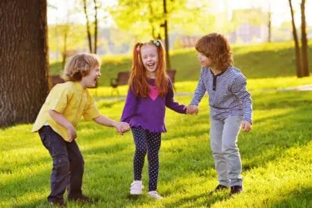 Group of children smiling while holding hands in the park