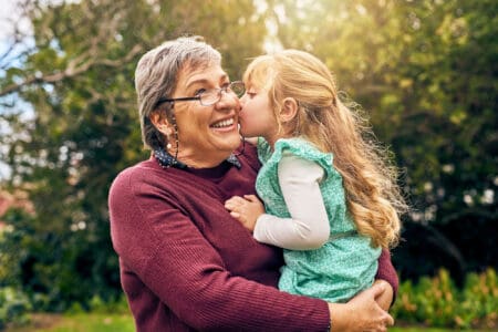 Cheerful granddaughter kissing her grandmother on the cheek at the park