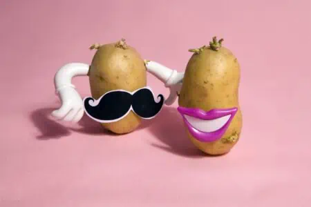 Funny potatoes with props on pink background