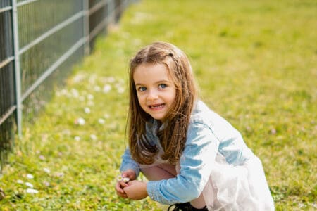 Cute little girl picking up some first spring flowers in the grass