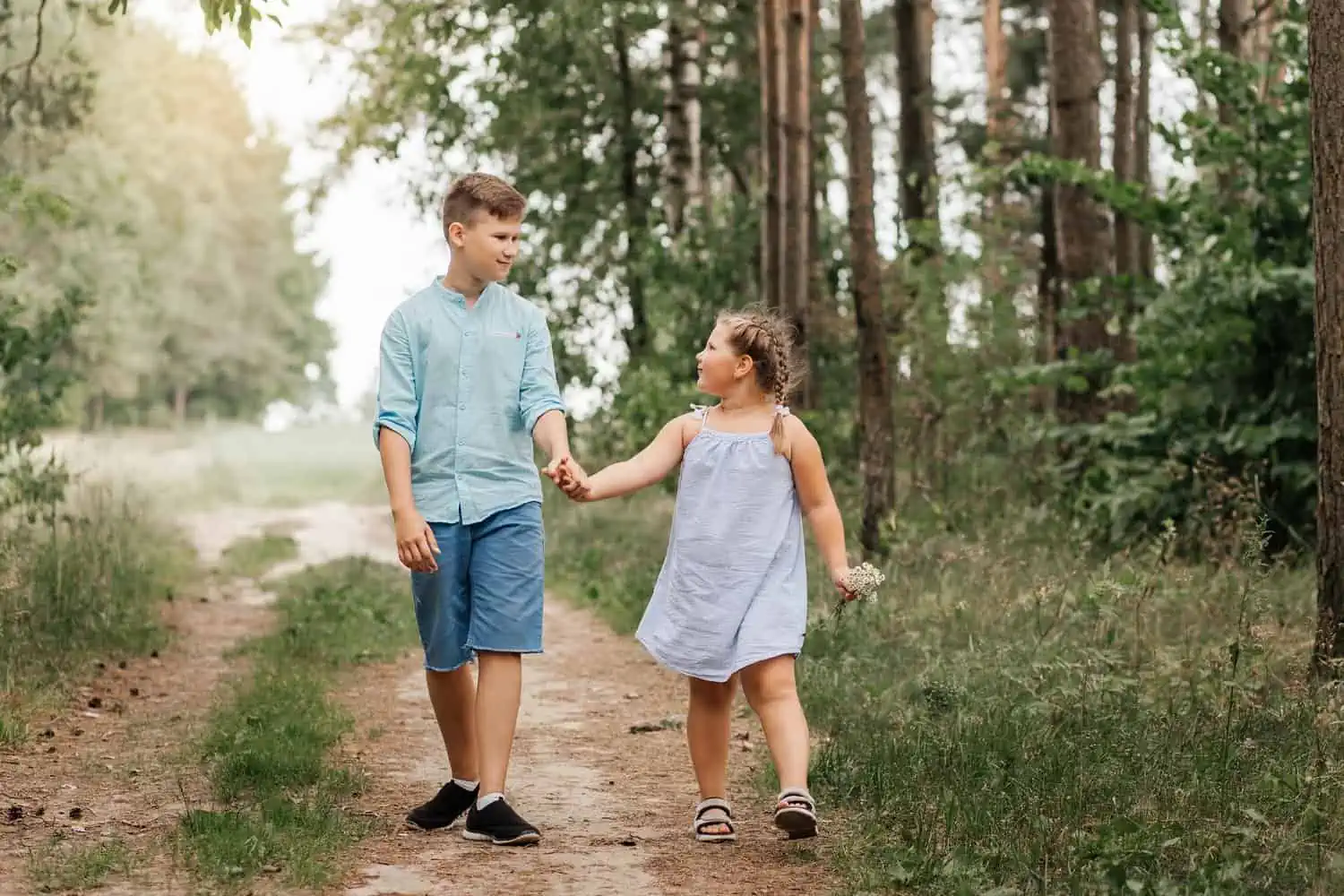 Cute sibling walking along forest path together