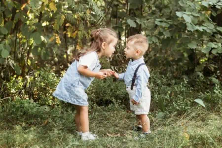 Adorable little girl talking to her younger brother in the park