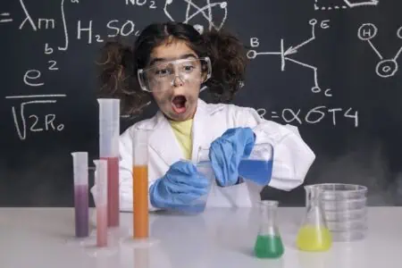 Funny little girl with gloves and goggles in lab coat mixing chemical flasks