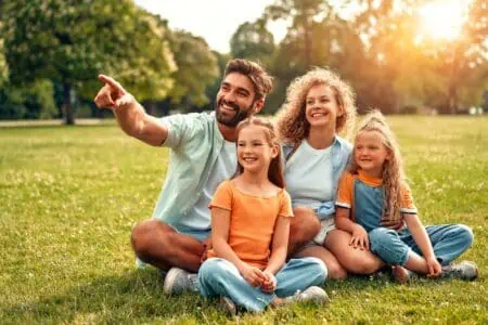 Happy family sitting on the grass in a meadow in the park