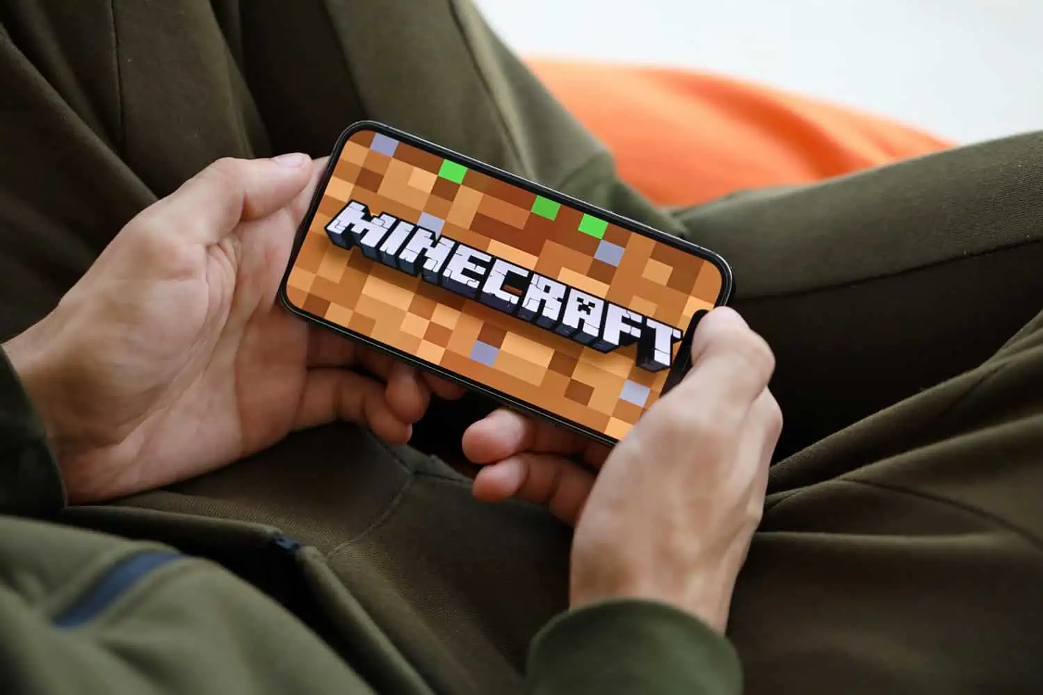 Man holdin smartphone with minecraft game