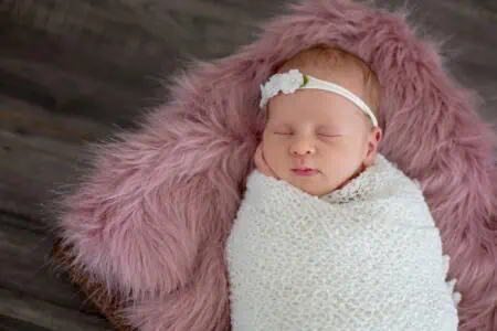 Little newborn baby girl sleeping on fur rug
