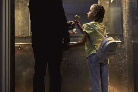 Unrecognizable man giving candy to a little girl in the elevator