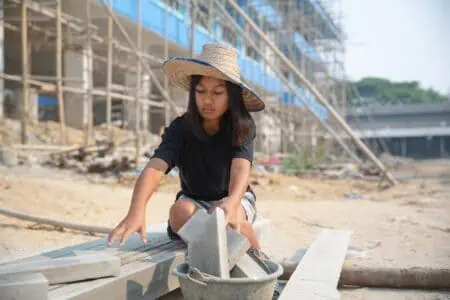 Young girl wearing hat working in construction site