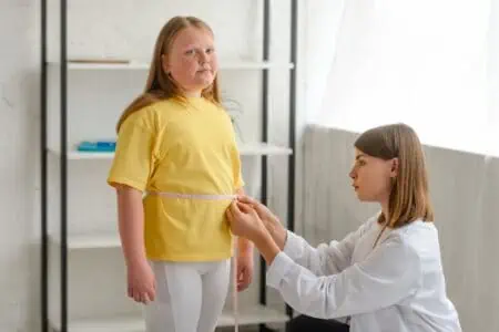 Doctor measuring young girl's waist