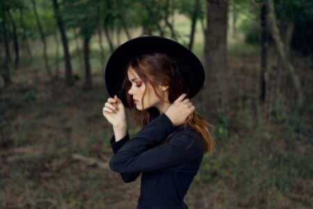Woman wearing black hat and top standing in the forest