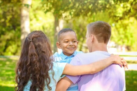 Happy little african american boy with her foster parents at the park