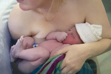 Mother embracing her newly born baby after a natural pool home birth