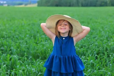 Pretty little girl wearing summer hat standing in the field