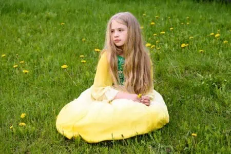 Young girl in yellow green dress sitting on the grass