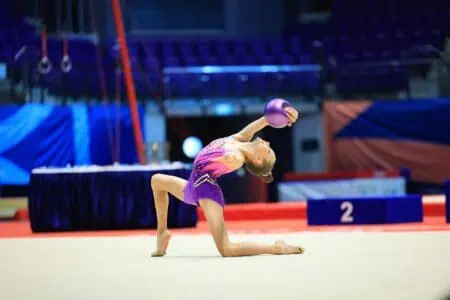 Girl gymnast showing ending pose with a ball in her floor routine