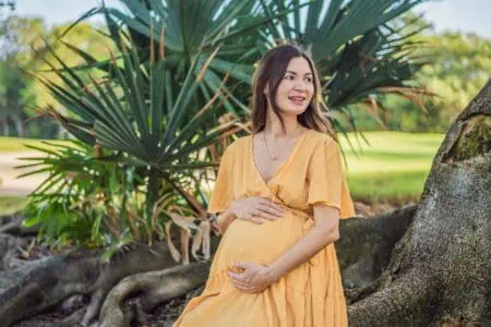 Pregnant woman after 40 in yellow dress sitting at the park