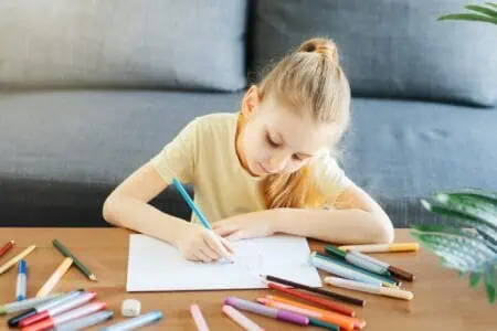 Young girl drawing on a paper with colored pen