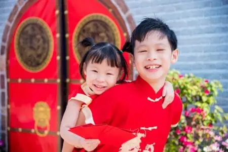 Chinese kids wearing traditional clothes smiling brightly while lookin at the camera
