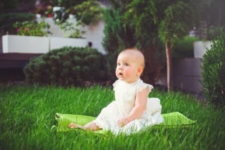 Adorable girl in dress sitting on the grass