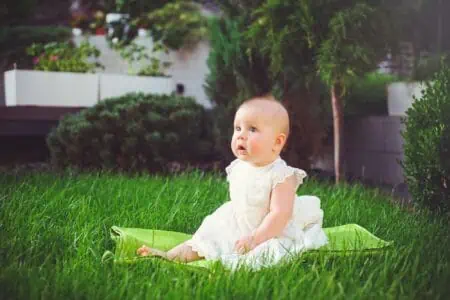 Adorable girl in dress sitting on the grass