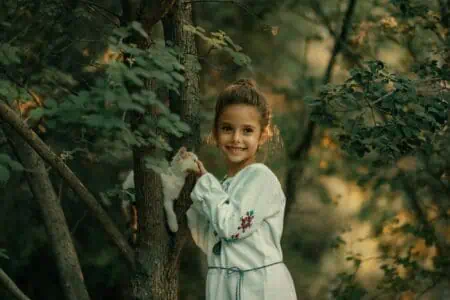 Young girl playing with kitten in the forest