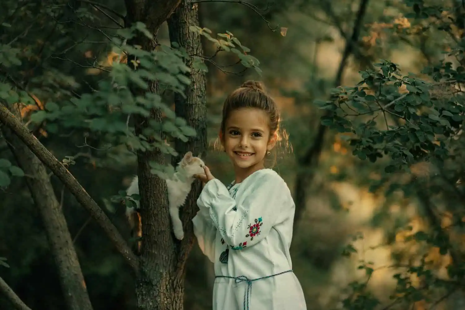 Young girl playing with kitten in the forest