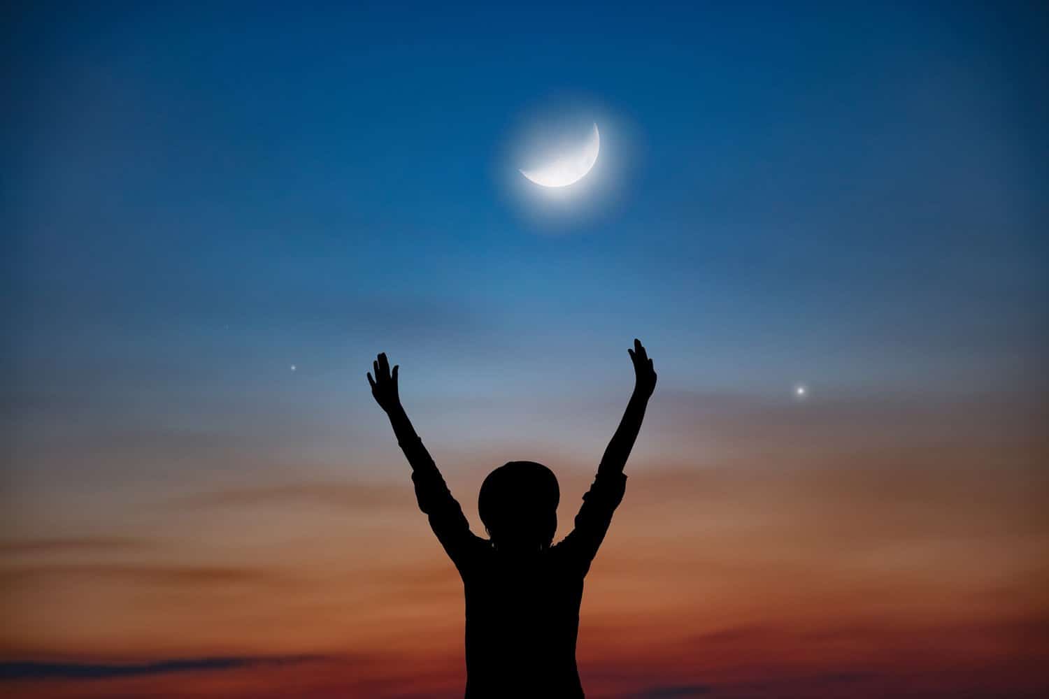 Silhouette of little boy against night sky with moon