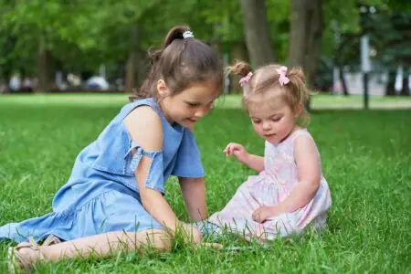 Two sisters sitting on the grass at the park