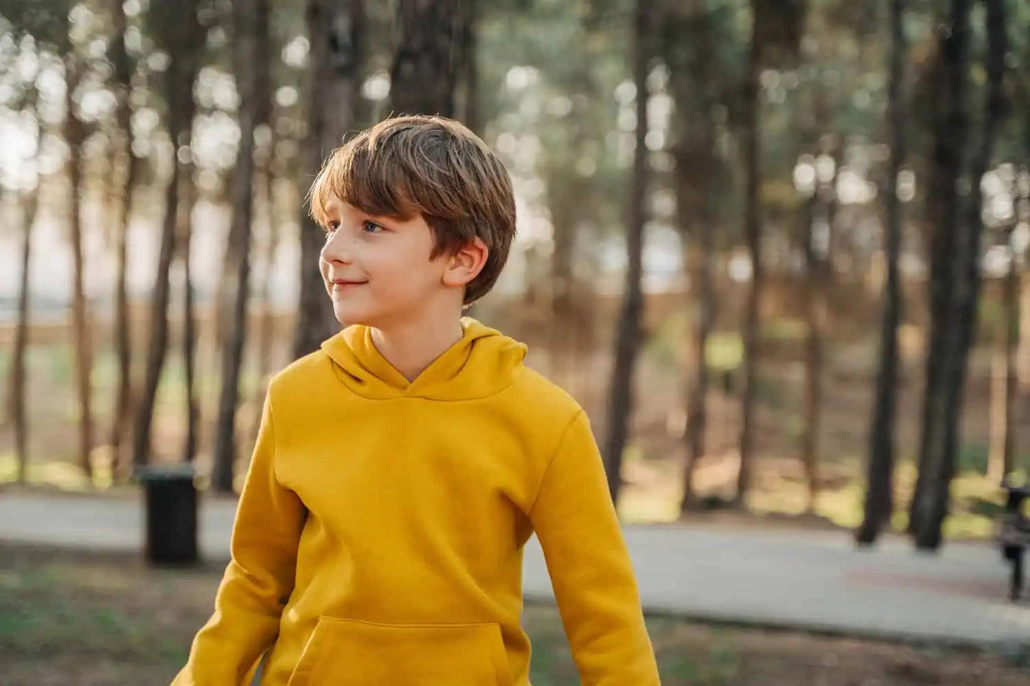 Adorable young boy in yellow jacket against forest background