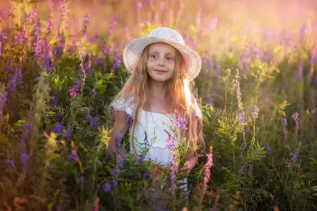 Adorable young girl wearing a hat at sunset in the field