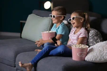 Kids eating popcorn while watching TV in the living room