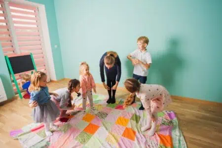 Kids copying the teacher touching their knees inside nursery room