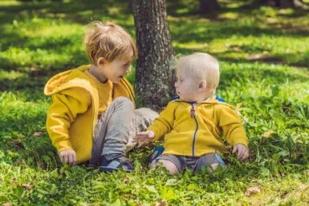 Happy brothers in yellow sweatshirts sitting at the autumn park