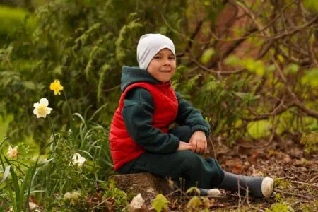 Smiling little boy sitting on tree stump at the park