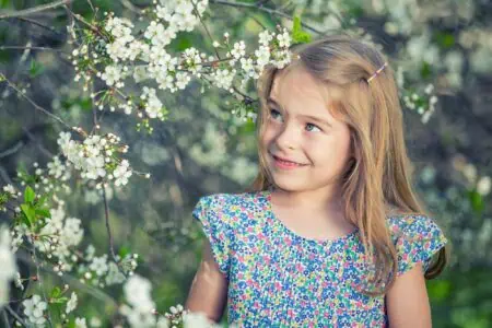 Blonde young girl looking at the flowers in the garden