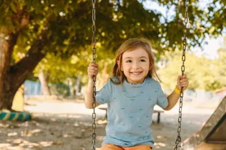 Beautiful young girl rocking on a swing at the park