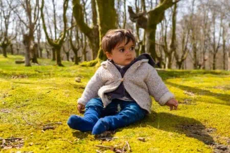 Cute little boy sitting on green grass at the park