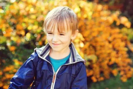 Smiling little boy playing in the autumn park