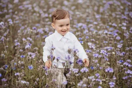 Cheerful boy standing in the field of flower