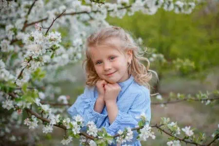 Pretty little girl posing near blooming tree