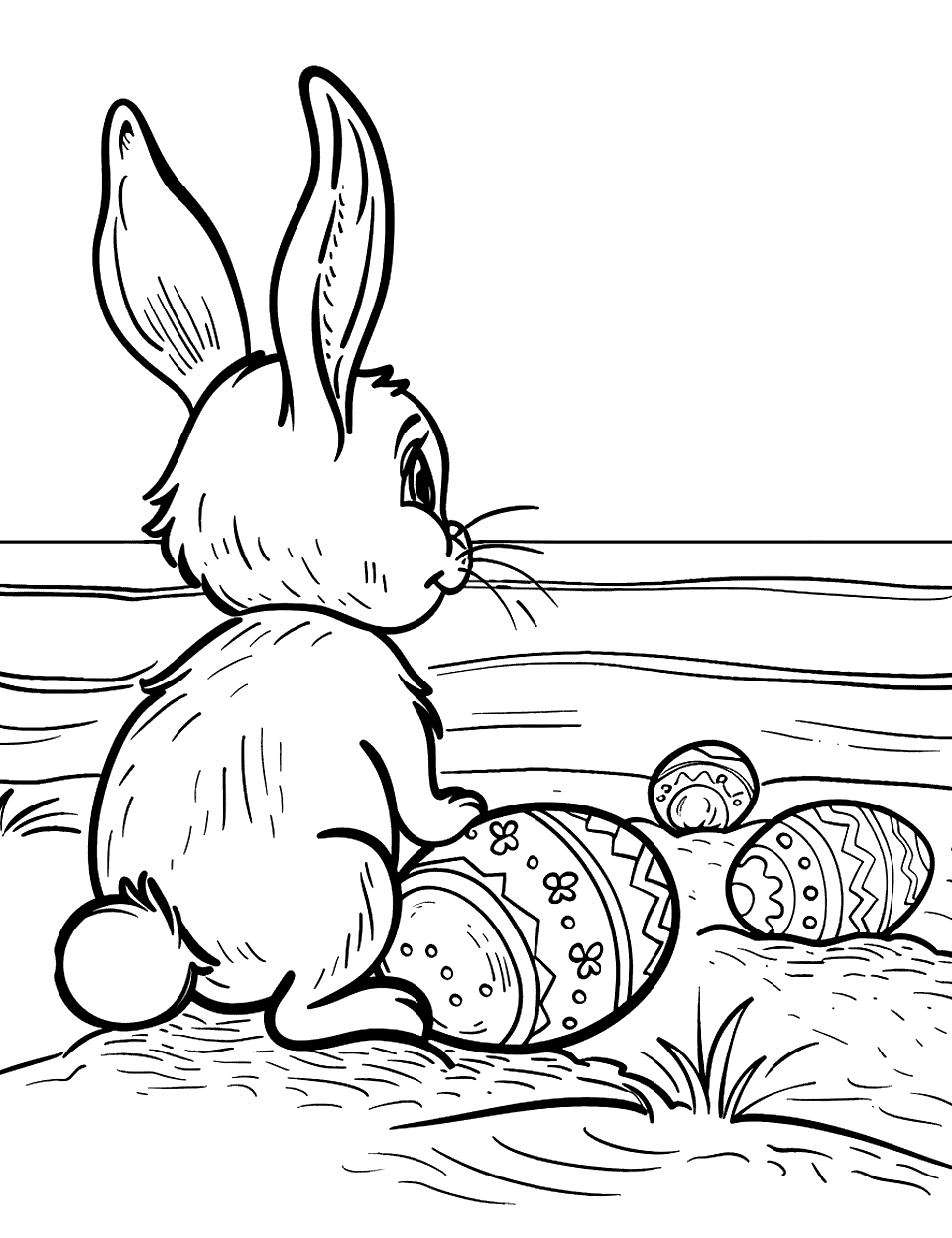 Seaside Easter Adventure Bunny Coloring Page - A bunny standing on a sandy beach looking at the sea, with a few Easter eggs scattered in the sand.