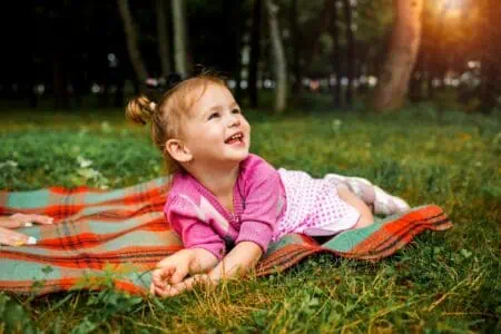 Adorable little girl lying on picnic blanket at the park