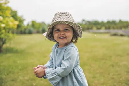 Adorable little girl in summer hat having fun in a lavender field.